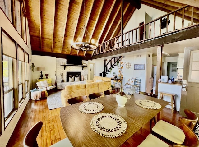 dining space with wooden ceiling, high vaulted ceiling, a fireplace, beamed ceiling, and wood-type flooring