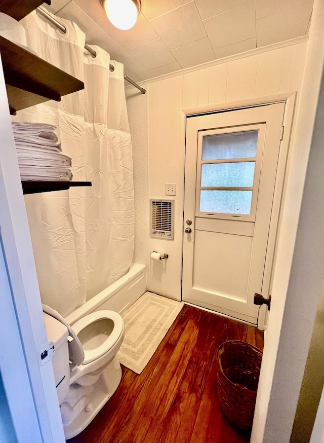 bathroom with hardwood / wood-style flooring, toilet, and shower / bath combo with shower curtain