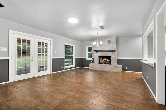 unfurnished living room with a fireplace, french doors, dark hardwood / wood-style floors, and a healthy amount of sunlight