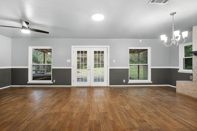 unfurnished living room featuring ceiling fan with notable chandelier, french doors, dark hardwood / wood-style flooring, and a fireplace