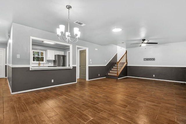 unfurnished living room featuring ceiling fan with notable chandelier and dark wood-type flooring