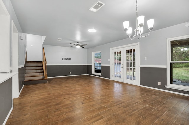 unfurnished living room featuring ceiling fan with notable chandelier, a healthy amount of sunlight, dark hardwood / wood-style flooring, and french doors