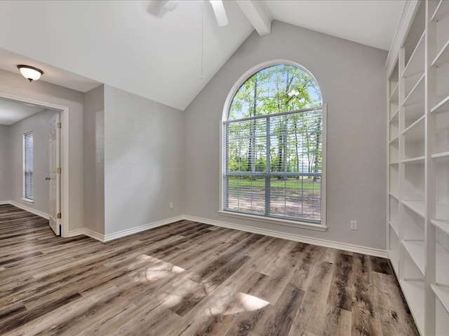 empty room with baseboards, a ceiling fan, wood finished floors, and vaulted ceiling with beams