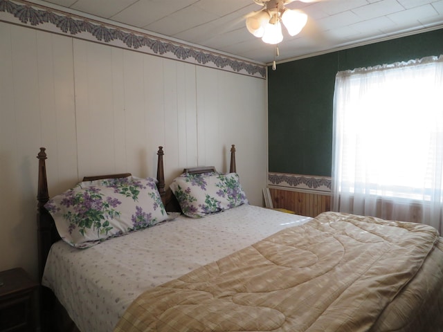 bedroom with ceiling fan and wooden walls