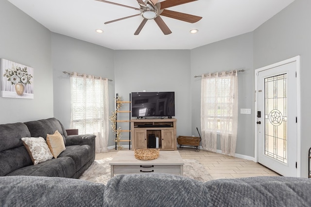 living room featuring ceiling fan, a wealth of natural light, and light wood-type flooring