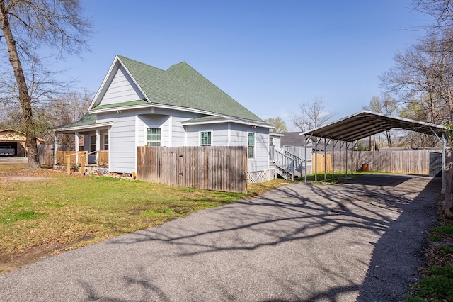 view of side of home featuring a carport, a porch, and a yard