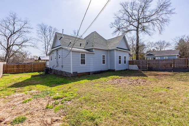 rear view of house featuring central AC unit and a lawn