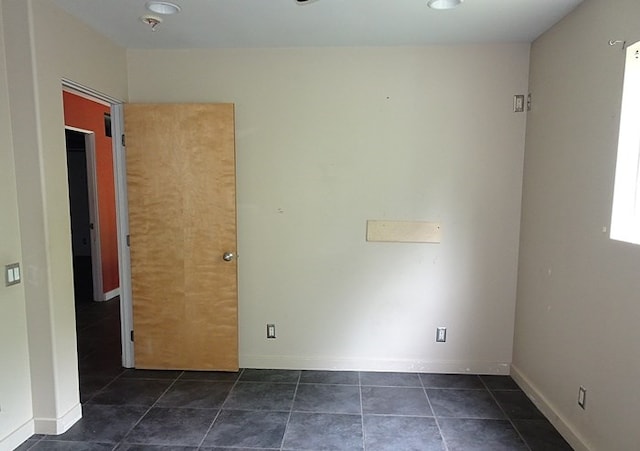 unfurnished room featuring dark tile patterned flooring