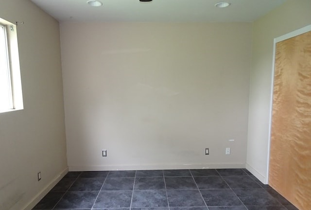 spare room with plenty of natural light and dark tile patterned flooring