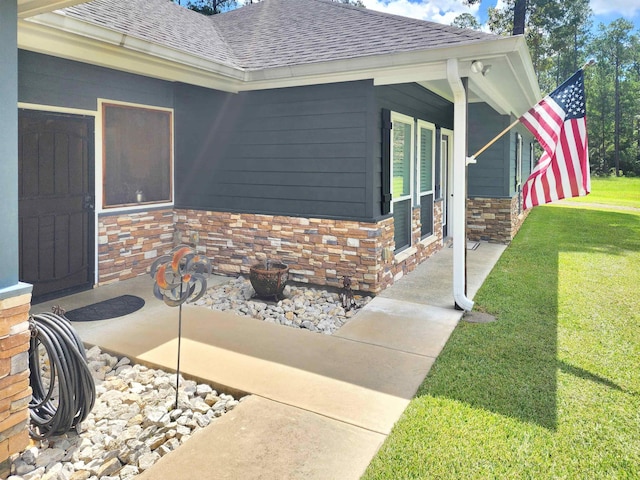 property entrance with a porch, a lawn, stone siding, and a shingled roof