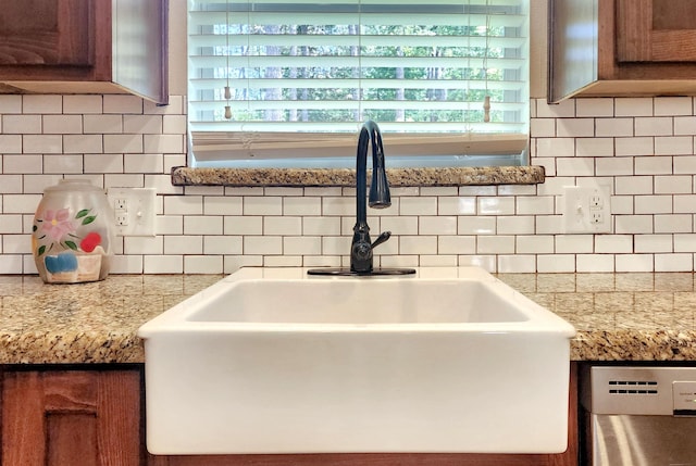 room details with brown cabinets, a sink, backsplash, stainless steel dishwasher, and light countertops