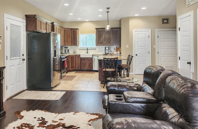 kitchen with backsplash, open floor plan, a breakfast bar area, appliances with stainless steel finishes, and a sink