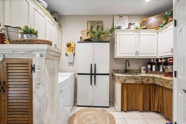 kitchen with light tile patterned floors, sink, white cabinetry, fridge, and dark stone counters