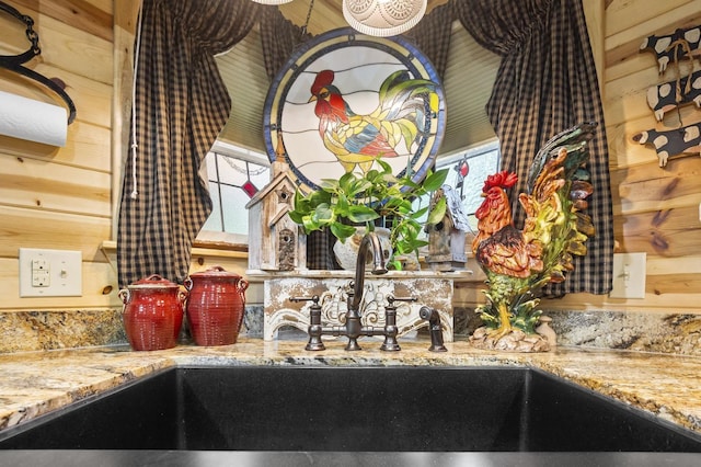 room details featuring sink, light stone countertops, and wood walls