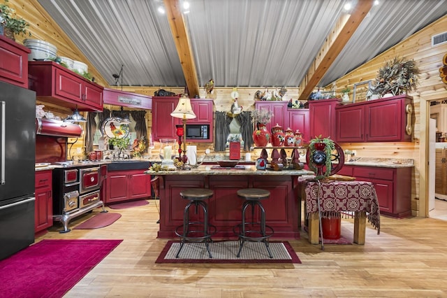 kitchen featuring high quality fridge, lofted ceiling with beams, black microwave, a center island, and light hardwood / wood-style flooring