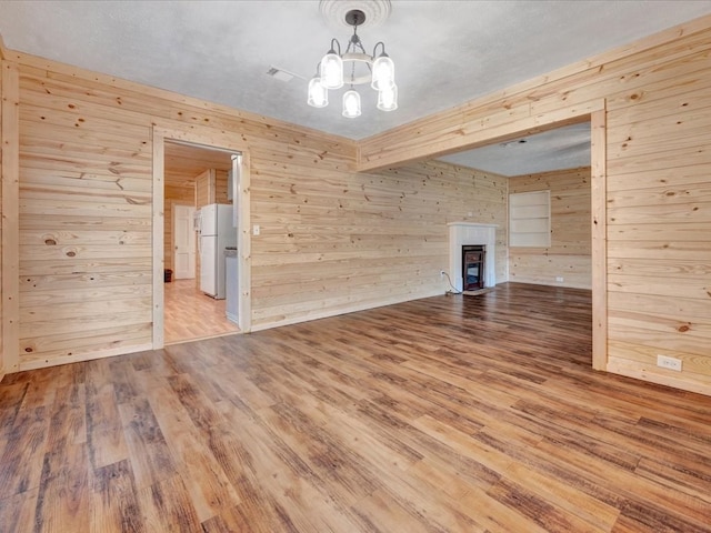 2524 US Highway 69 N, Lufkin, TX 75904 - empty room featuring wooden walls, wood finished floors, a chandelier, and a glass covered fireplace