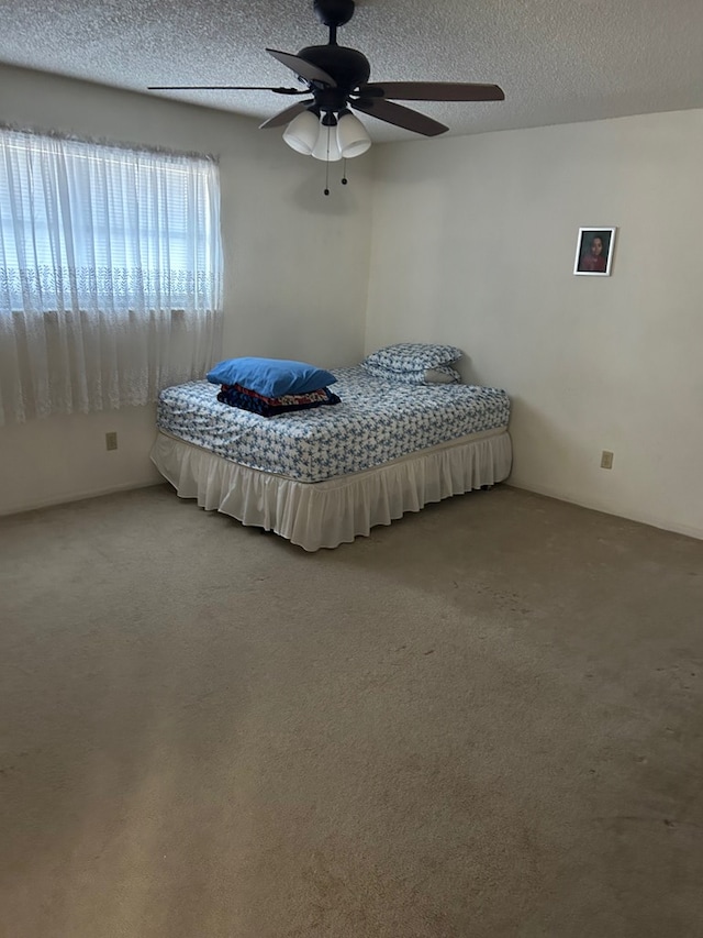 unfurnished bedroom featuring ceiling fan, carpet floors, and a textured ceiling