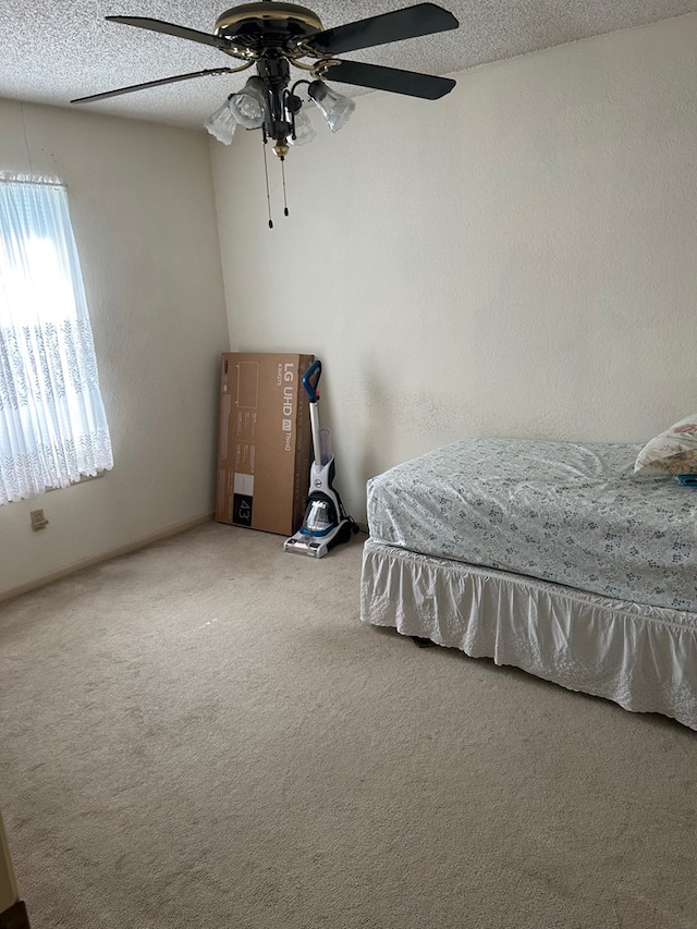 carpeted bedroom with ceiling fan and a textured ceiling