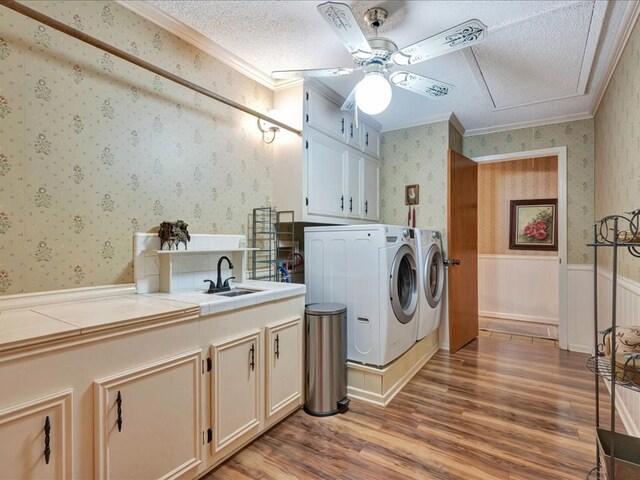 laundry room featuring cabinets, wood-type flooring, ornamental molding, and washing machine and clothes dryer