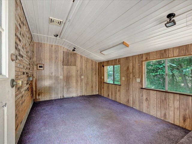 carpeted spare room with wood walls, wooden ceiling, lofted ceiling, and brick wall