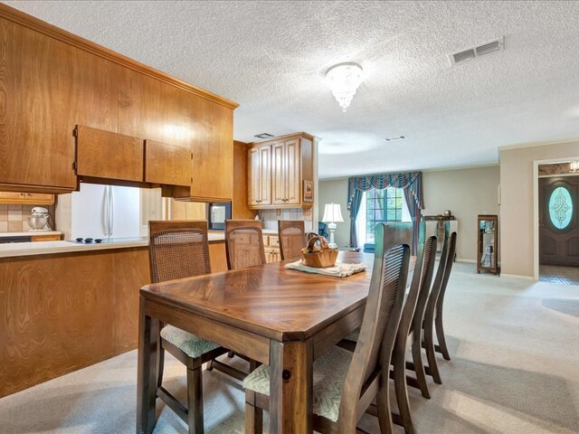 dining room featuring light colored carpet and a textured ceiling