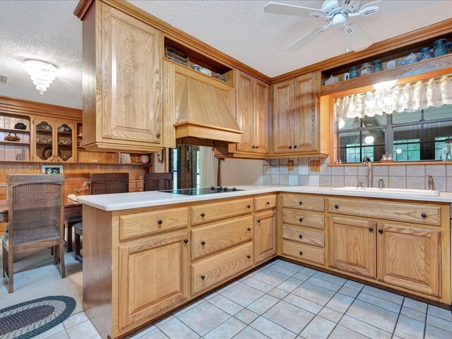 kitchen featuring kitchen peninsula, custom range hood, a textured ceiling, black stovetop, and light tile patterned flooring