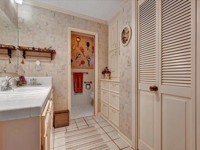 bathroom featuring vanity, a textured ceiling, crown molding, tile patterned flooring, and toilet