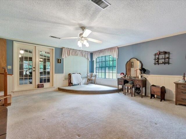 sitting room with ceiling fan, french doors, a textured ceiling, carpet, and ornamental molding