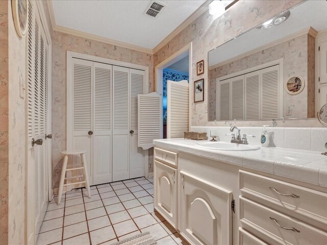 bathroom with tile patterned flooring, vanity, a textured ceiling, and ornamental molding