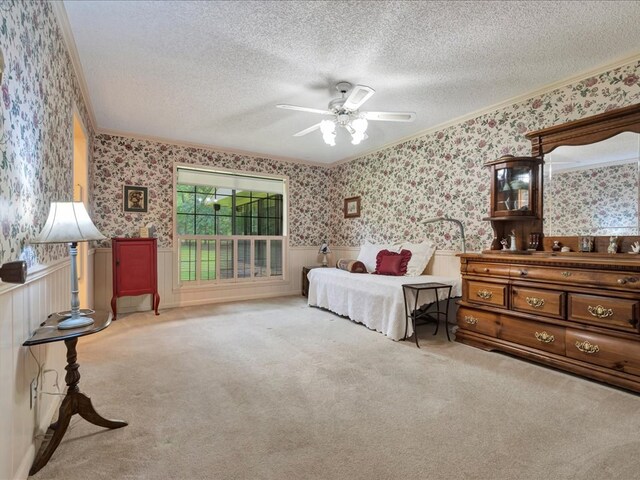 bedroom with ceiling fan, crown molding, light colored carpet, and a textured ceiling