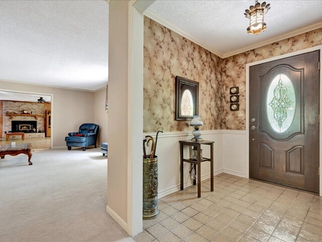 foyer featuring crown molding, light colored carpet, a textured ceiling, and a brick fireplace