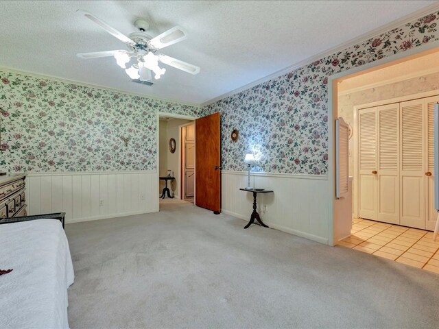 unfurnished bedroom featuring ceiling fan, crown molding, light colored carpet, and a textured ceiling