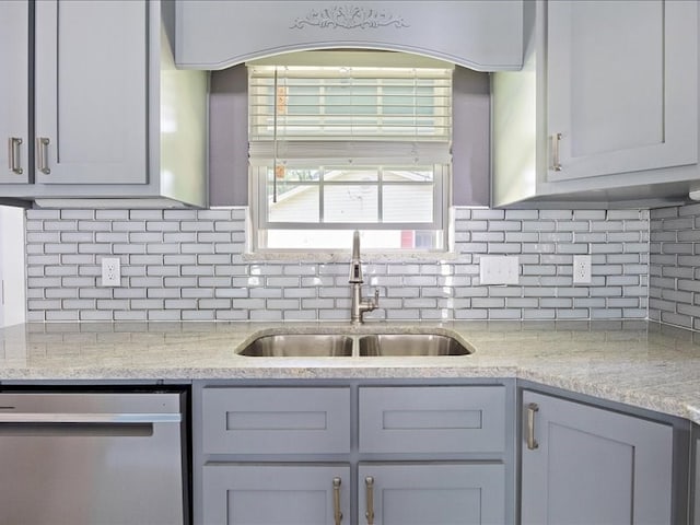 kitchen with dishwasher, tasteful backsplash, light stone countertops, and sink