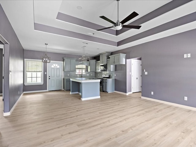 kitchen with pendant lighting, a center island, a raised ceiling, and stainless steel appliances