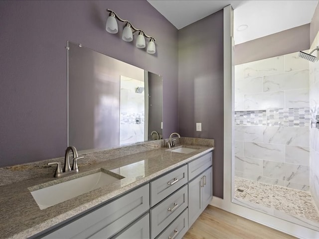 bathroom featuring hardwood / wood-style floors, vanity, and a tile shower