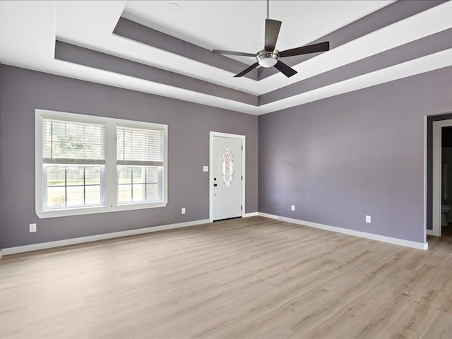 interior space featuring light wood-type flooring, a raised ceiling, and ceiling fan