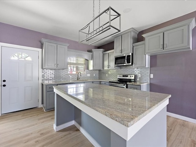 kitchen featuring sink, stainless steel appliances, light hardwood / wood-style flooring, gray cabinets, and a kitchen island