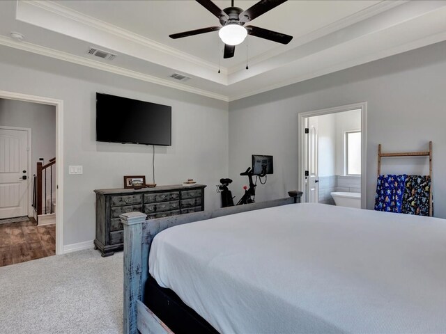 carpeted bedroom with a raised ceiling, connected bathroom, ceiling fan, and crown molding