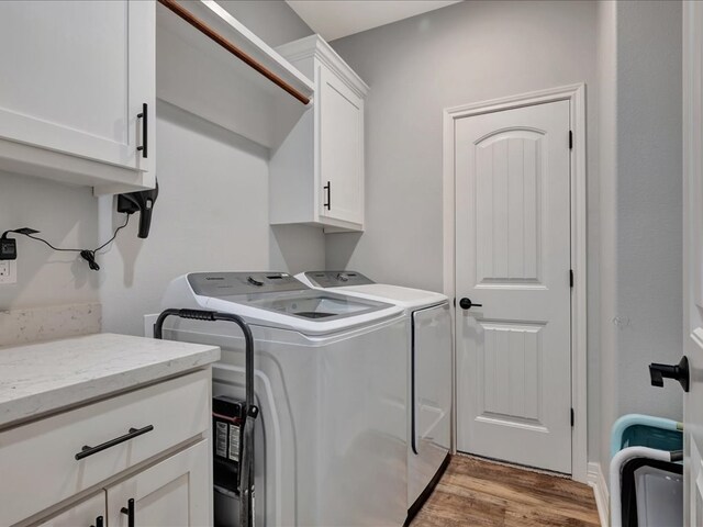 laundry room with washer and clothes dryer, cabinets, and light hardwood / wood-style flooring