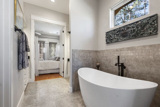 373 Duffer Dr, Brookeland, TX 75931 - ensuite bathroom with tile walls, a freestanding bath, tile patterned flooring, recessed lighting, and a wainscoted wall
