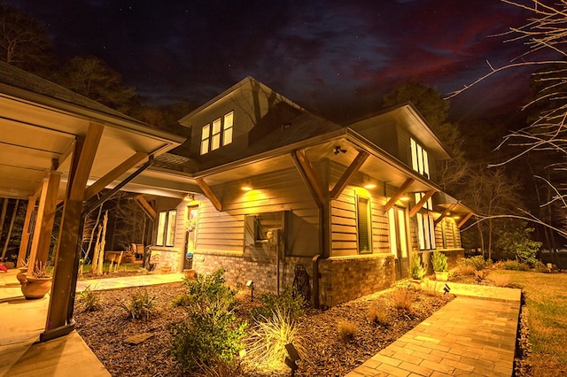 property exterior at twilight with stone siding