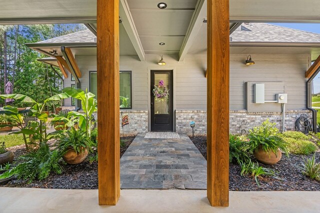 373 Duffer Dr, Brookeland, TX 75931 - view of exterior entry with roof with shingles, stone siding, and a porch