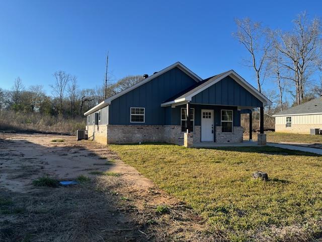 view of front of house with a porch, cooling unit, board and batten siding, and a front lawn