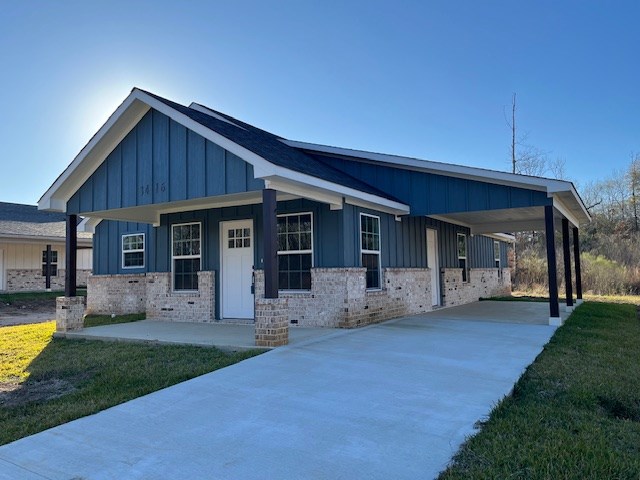 view of front of property with a front lawn, covered porch, board and batten siding, concrete driveway, and a carport