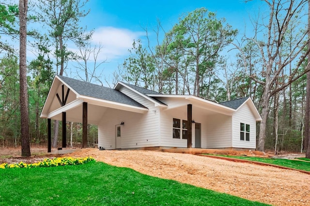 725 Arborcrest Dr, Brookeland, TX 75931 - view of front of house with a carport, dirt driveway, a shingled roof, and a front yard