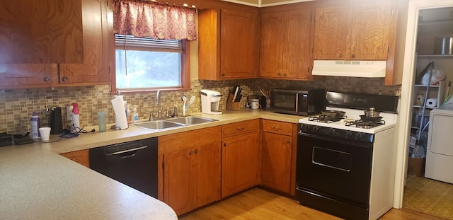 kitchen with light hardwood / wood-style floors, sink, black appliances, and washer / dryer