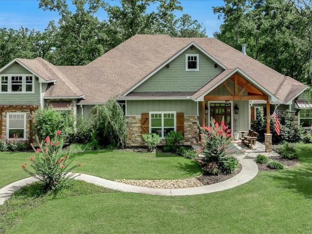 410 Brentwood Dr, Lufkin, TX 75901 - craftsman-style home featuring stone siding, a front yard, a shingled roof, and covered porch