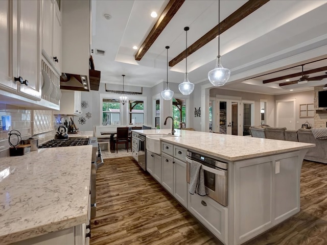 410 Brentwood Dr, Lufkin, TX 75901 - kitchen with dark wood-style floors, stainless steel appliances, white cabinets, beamed ceiling, and a spacious island