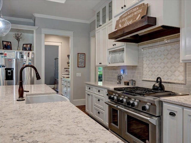 410 Brentwood Dr, Lufkin, TX 75901 - kitchen featuring appliances with stainless steel finishes, custom range hood, white cabinets, tasteful backsplash, and glass insert cabinets