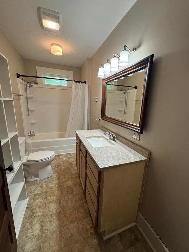 bathroom with toilet, vanity, shower / tub combo with curtain, stone finish flooring, and a textured ceiling
